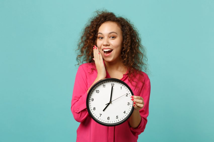 Happy young woman with a round clock