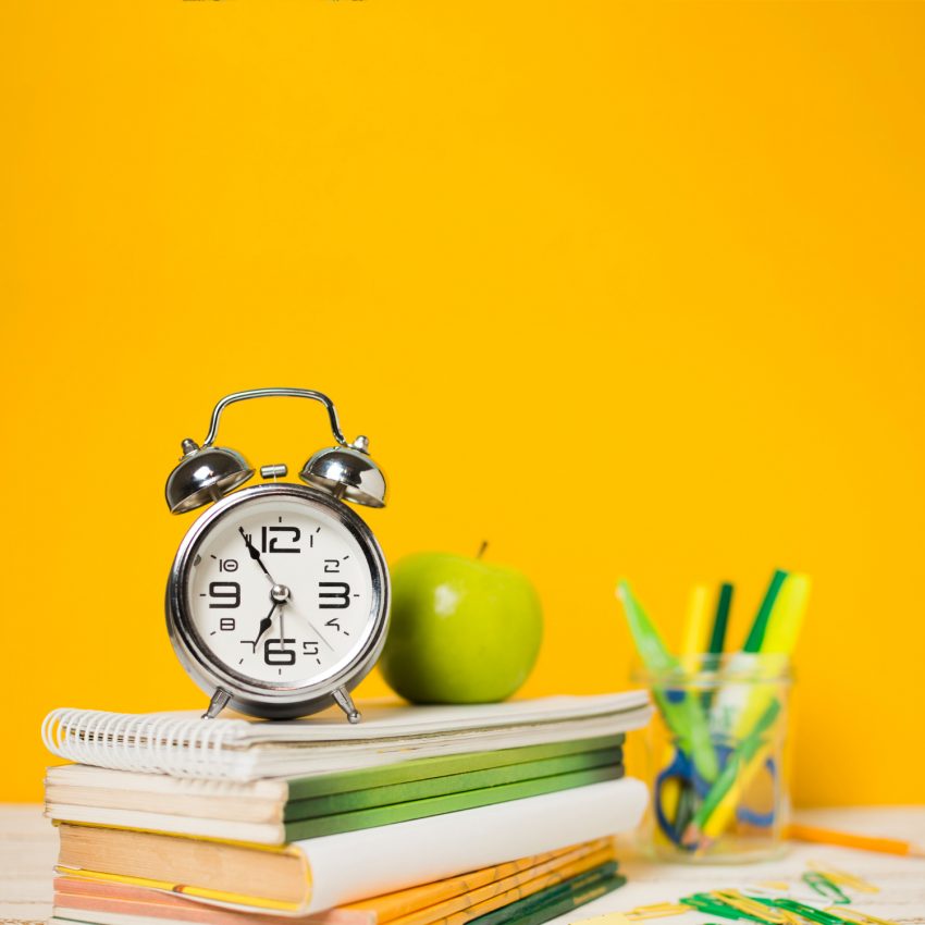 Clock, apple and books on the table