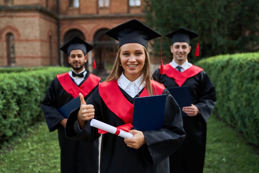 Graduated students are holding diplomas and smiling