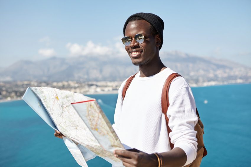 Happy male traveler with a paper map